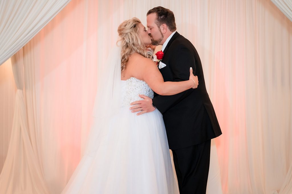 Bride and groom first kiss as husband and wife at Georgios Banquets in Orland Park, IL