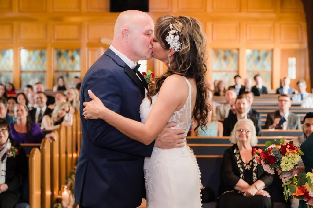 Bride and groom first kiss from behind the altar at The Center, in Itasca, IL