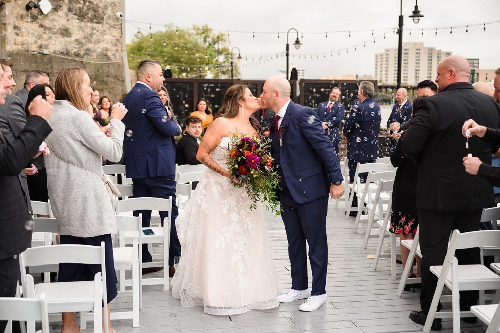 Bride and groom kiss during their recessional at Prairie Street Brewing Company in Rockford, IL