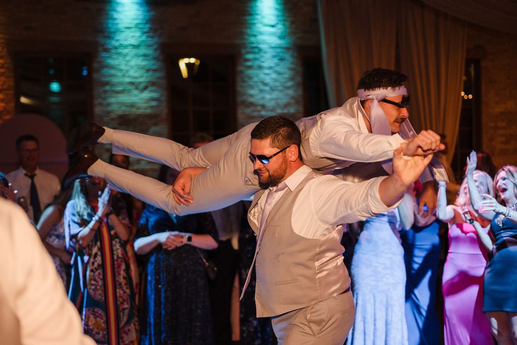 Groomsmen lifts other groomsmen during the wedding reception at The BRIX on the Fox in Carpentersville, IL